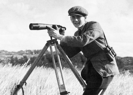 Junger Heinz steht am Spektiv in einer Dünen-Landschaft