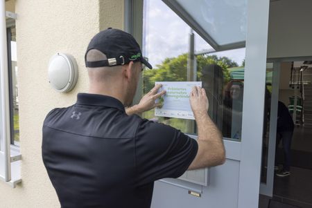 Ruben de Graaf, CEO von SpirStar, klebt ein Schild an die Eingangstür des Unternehmens, auf dem steht, dass das Firmengelände besonders naturnah gestaltet wurde.