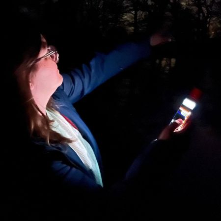 Frau bei einer abendlichen Fledermaus-Exkursion mit Detektor in der Hand