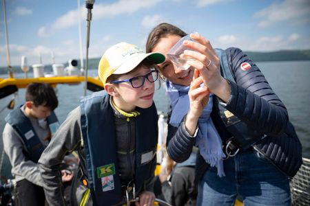 Schüler inspiziert Probe des Bodensees in einem Glas