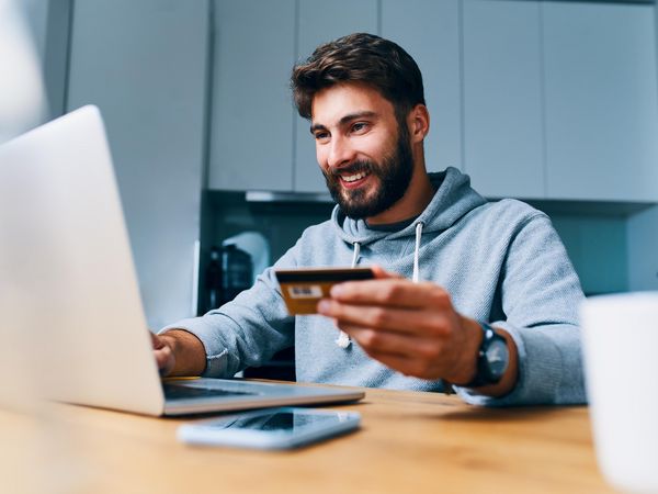 Lachender Mann kauft am Computer ein