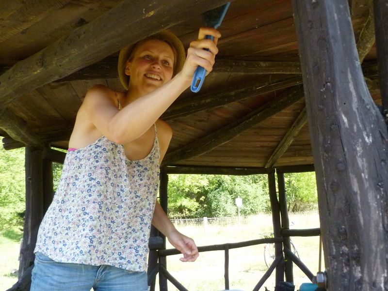 Frau streicht Wanderhütte mit neuer Farbe an 