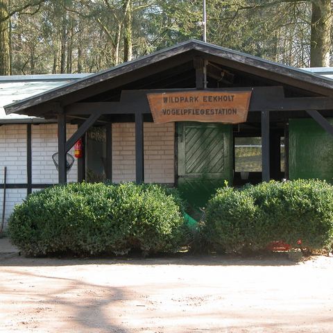 Haus mit Schild auf dem "Wildpark Eekholt Vogelpflegestation" steht, im Hintergrund Wald.