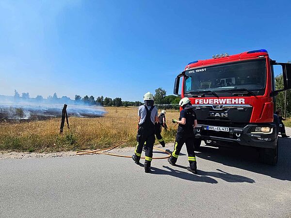 Zwei Feuerwehrleute stehen vor einem roten Feuerwehrauto.