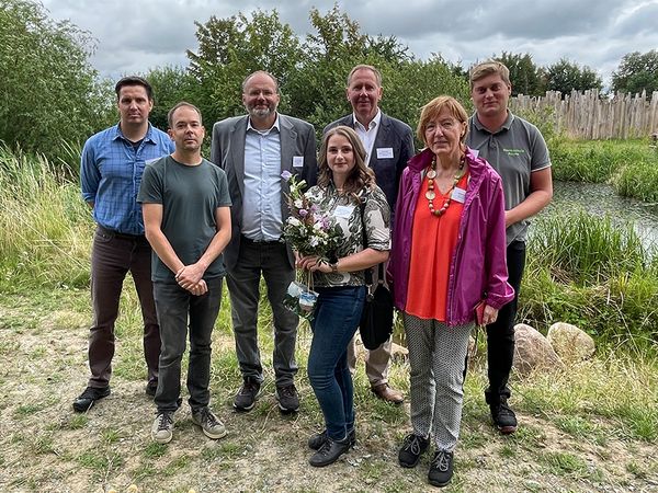 Gruppenfoto mit sieben Personen vor einem naturnahen Teich.