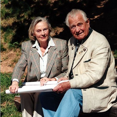 Heinz und Inge Sielmann sitzen im Freien auf einer Holzbank mit einem Plan auf dem Schoß