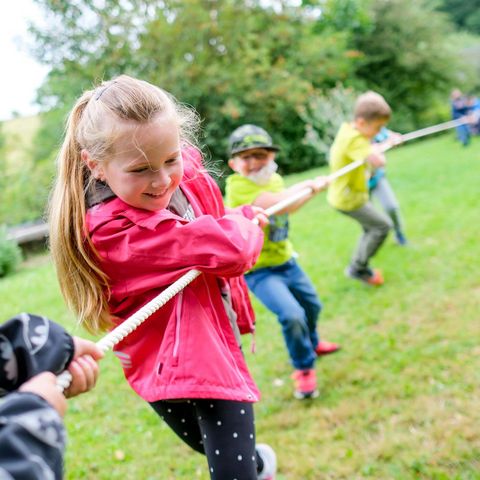 Kinder beim Tauziehen im Grünen